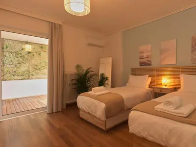 a bedroom with two beds and a large window at Vouliagmeni Seaside Luxury Home in Athens