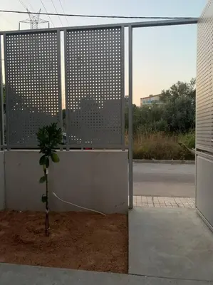 a small tree in front of a building with a fence at Vasiliki’s Guesthouse II in Athens