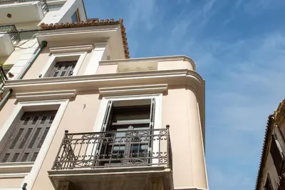 a white building with a balcony and a blue sky at Epitome Suites in Athens