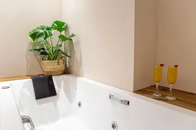 a bathroom with a tub with two glasses and a plant at Epitome Suites in Athens