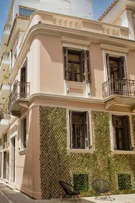 a building with a ivy covered wall and two chairs at Epitome Suites in Athens