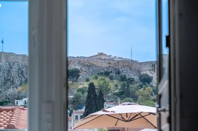 a view of a mountain from a window with an umbrella at Plaka Apartments - Acropolis View in Athens