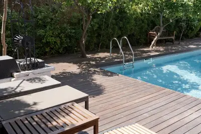 a wooden deck next to a swimming pool with a bench at Lussuosa Villa Glyfada in Athens