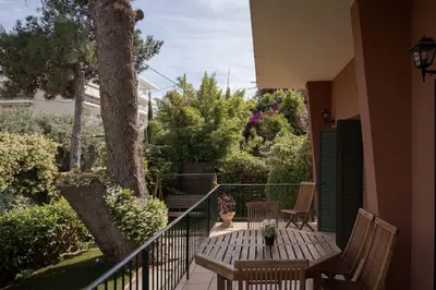 a porch with a table and chairs and a tree at Lussuosa Villa Glyfada in Athens
