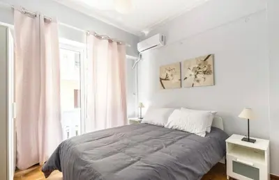 a white bedroom with a bed and a window at Cosy Central Apartment in Plaka in Athens