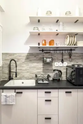 a kitchen with white cabinets and a black counter top at Cosy Central Apartment in Plaka in Athens