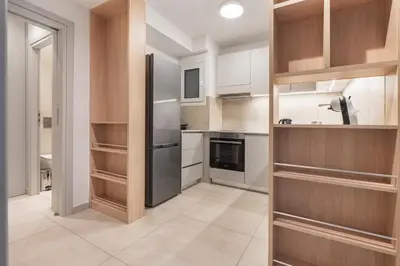 a kitchen with wooden cabinets and a stainless steel refrigerator at Oculus Gelonos 1 BD City Apartment by Live&Travel in Athens