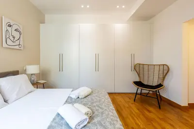 a bedroom with a bed and a chair and white cabinets at Holodek Apartments : Akropolis in Athens