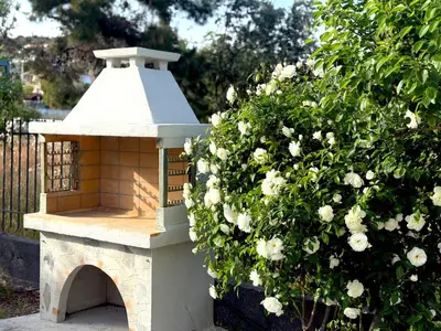 a bird house sitting next to a bush with flowers at Arcus by Aestas Suites in Artemida