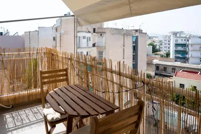 a balcony with a wooden table and chairs on a building at Serene 1BR Apartment in the Heart of Athens in Athens