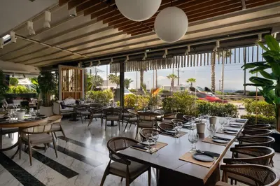 a dining room with tables and chairs and windows at Coral Three-Bedroom Apartments with Sea View and Balcony in Athens
