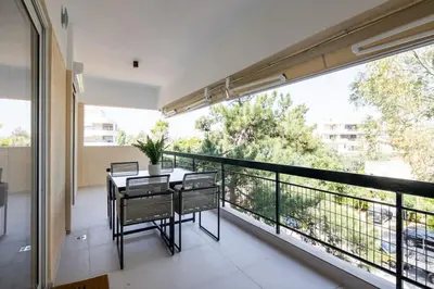 a balcony with a table and chairs and a large window at Bloom - Luxury 2-Bedroom Apartment in Athens in Athens