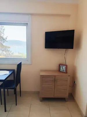 a room with a table and a television on a wall at Studio with unique view near the beach! in Porto Rafti