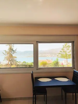 a table and two windows with a view of the ocean at Studio with unique view near the beach! in Porto Rafti