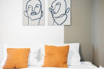 two art prints above a bed with orange pillows at Luxury Beachfront Suite in Voula Premium 2-Bedroom Stay in Athens