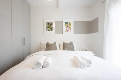 a white bedroom with a bed with towels on it at Luxury Beachfront Suite in Voula Premium 2-Bedroom Stay in Athens