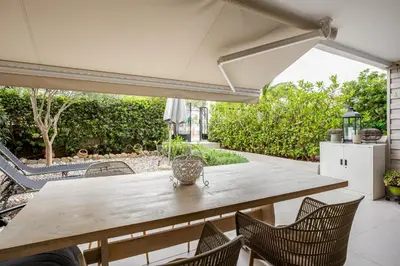 an outdoor dining table with chairs and an umbrella at Atlantis Riviera Beachfront Fast WiFi in Athens