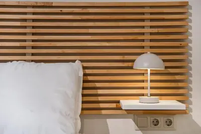 a bed with a wooden headboard with a lamp on a table at Atlantis Riviera Beachfront Fast WiFi in Athens