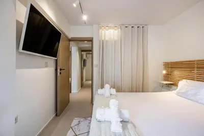a bedroom with a white bed with a flat screen tv at Atlantis Riviera Beachfront Fast WiFi in Athens