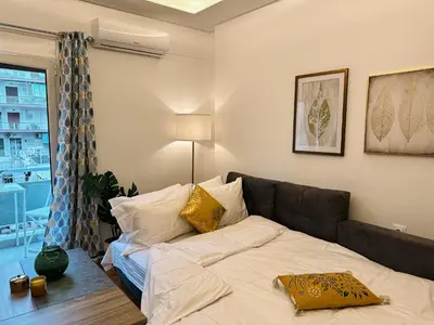 a bedroom with a bed and a couch and a window at Acropolis Aria Apartment-Steps to Metro & Tram in Athens