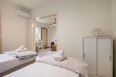 a white room with two beds and a mirror at Athens Riviera Hermes Coastal Residence in Athens