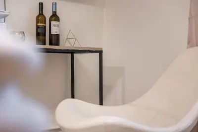 a table with three bottles of wine and a white chair at Athens Riviera Hermes Coastal Residence in Athens