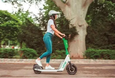a woman riding a scooter down the street at Athens Riviera Hermes Coastal Residence in Athens