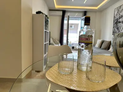 a bottle of alcohol sitting on a table with two glasses at Kypseli Contemporary Comfort for 6 in Athens