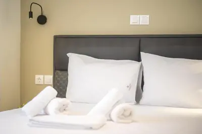 a white bed with white pillows and a black headboard at Three Bedroom Stylish Apt next to Acropolis in Athens