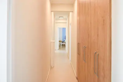 a corridor with wooden doors in a white hallway at Spacious apartment in Athens in Athens