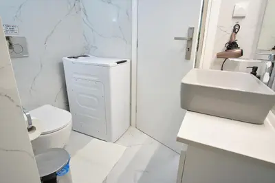 a white bathroom with a toilet and a sink at Central Cozy House in Athens