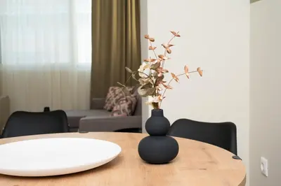 a black vase with flowers on a wooden table at Elegant Zen 2BR Apartment in Athens in Athens