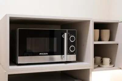 a microwave oven in a cabinet with cups and vases at Elegant Comfort 2BR Apartment in Athens in Athens