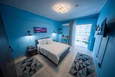 a blue bedroom with a bed and a window at Lux Apartment next to the sea in Piraeus