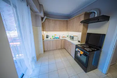 a small kitchen with a stove and a tv at Lux Apartment next to the sea in Piraeus
