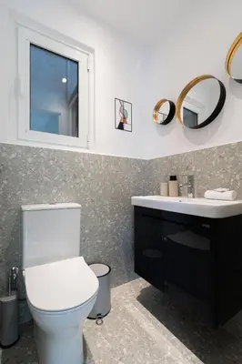 a bathroom with a toilet and a sink and a mirror at Elegant Escape 2BR BA Sunny Apt in Athens