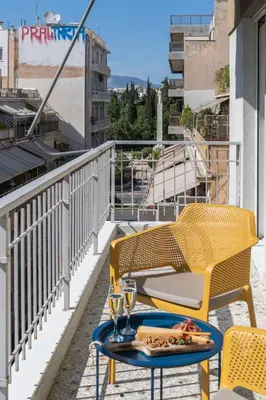 a table and chairs on the balcony of a building at Elegant Escape 2BR BA Sunny Apt in Athens