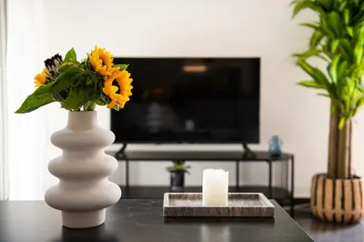 a white vase with flowers and a candle on a table at Glyfada First Class Suite by First Class Properties in Athens