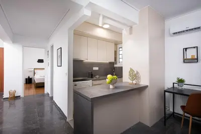 a kitchen with white cabinets and a black counter top at Glyfada First Class Suite by First Class Properties in Athens