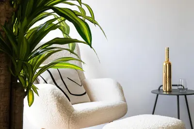 a living room with a white chair and a plant at Glyfada First Class Suite by First Class Properties in Athens