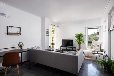 a white living room with a couch and a tv at Glyfada First Class Suite by First Class Properties in Athens