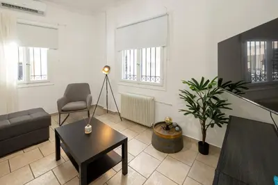 a living room with a couch a table and a tv at Phaedrus Living Athens City Studios Paris in Athens