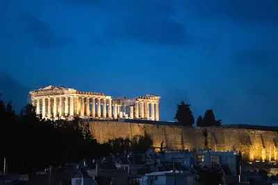 a building on top of a hill at night at Acropolis Landscape in Athens