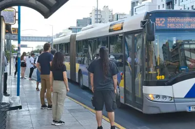 a group of people waiting for a bus at a bus stop at Acropolis Landscape in Athens
