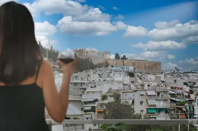 a woman holding a glass of wine looking at a city at Acropolis Landscape in Athens