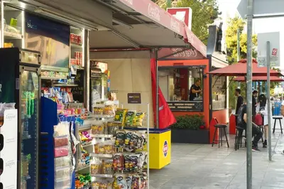 a store on a street with people sitting outside of it at Acropolis Landscape in Athens