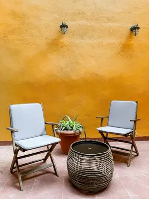 two chairs and a table in front of a yellow wall at Ανακαινισμένο σπίτι με ιδιωτική αυλή in Piraeus