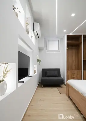 a white bedroom with a bed and a chair at CityLiv Concept in Athens