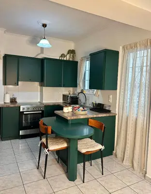 a kitchen with green cabinets and a table and chairs at Urban lodge Agios Dimitrios in Athens