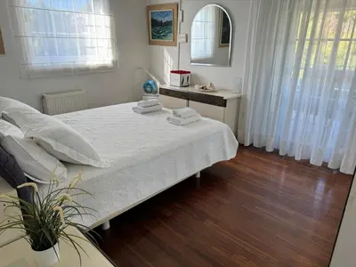 a bedroom with a bed with white sheets and a mirror at Vouliagmeni Seaside Escape in Athens